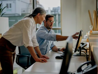 A man and a woman looking at a computer screen in an office