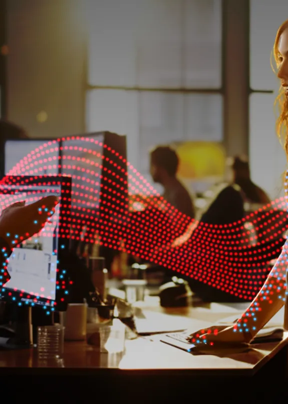 Man and woman talking by a computer monitor 